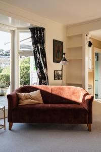 Sofá marrón en la sala de estar con ventana en Cottage on Aotea, en Dunedin