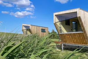 une maison en bois dans un champ d'herbe haute dans l'établissement Sleep Space 4 - Green Tiny Spot Cuxhaven Altenbruch, à Cuxhaven