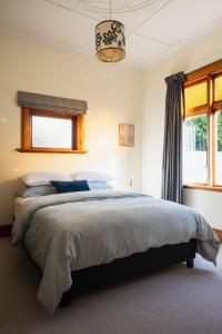 um quarto com uma cama grande e uma janela em Cottage on Aotea em Dunedin