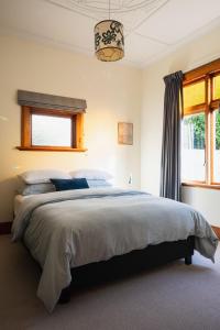a bedroom with a large bed and a window at Cottage on Aotea in Dunedin