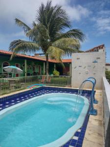 a swimming pool with a palm tree in front of a house at POUSADA LUATOUR Praia Pontal do Coruripe in Coruripe