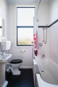 a bathroom with a toilet and a tub and a sink at Cottage on Aotea in Dunedin