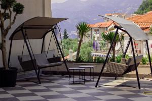 un patio con 2 columpios, mesa y sillas en Vertmont Apartments, en Sveti Stefan
