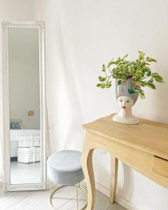 un vaso con una pianta su un tavolo accanto a uno specchio di VALÚ a Carloforte