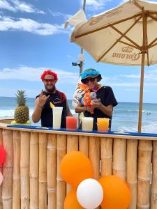 dos personas de pie en un bar en la playa en The Point Mancora - Beach Party Hostel, en Máncora