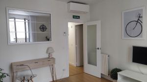 Sala de estar blanca con espejo y TV en Ibarrenea Apartamento, en Pamplona
