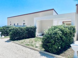 a white house with bushes in front of it at B&B L'EDEN DI CAPO BIANCO in Montallegro