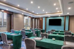 une salle de conférence avec des tables et des chaises vertes et une télévision à écran plat dans l'établissement Blossom Hotel Houston, à Houston