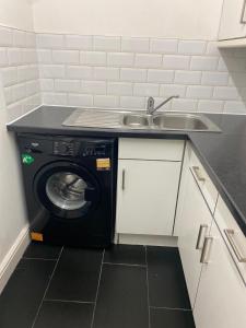 a kitchen with a sink and a washing machine at Streatham high street in London