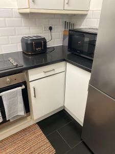 a kitchen with white cabinets and a black counter top at Streatham high street in London