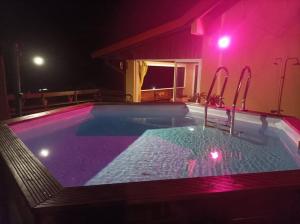 uma piscina à noite com luzes roxas em La Villa de Petite Anse - Piscine em Les Anses-dʼArlets