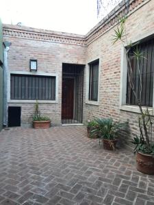 a brick building with a courtyard with potted plants at Costanera in San Nicolás de los Arroyos