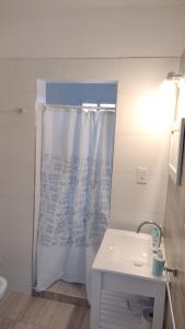y baño con cortina de ducha y lavamanos. en Casa Faziano en Guaymallén