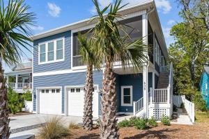 a blue house with palm trees in front of it at Maison by The Sea at Kure Beach in Kure Beach