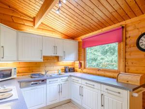 una cocina con armarios blancos y un reloj en la pared en Scandinavian Lodge - Uk37188 en Legbourne