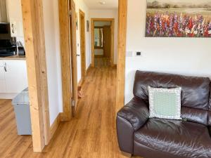 a living room with a leather couch and a painting at Aylesbury Lodge in Halstead