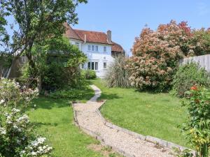 a garden with a white house and a pathway at Hop House in Hastings