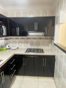 kuchnia z czarnymi szafkami i kuchenką w obiekcie Apartamento 2 habitaciones w mieście Barranquilla