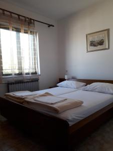 Un dormitorio con una cama con sábanas blancas y una ventana. en Apartments with parking space Pag - 18325, en Pag