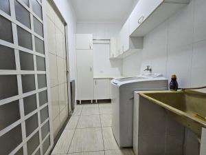 bagno bianco con lavandino e lavatrice di Casa do Sonho, Piscina, Sinuca, Churrasqueira a Maringá