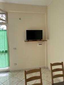 a living room with two chairs and a tv on a wall at In famiglia apartment and rooms for Pompei, Amalfi, Sorrento and Salerno in Sant'Egidio del Monte Albino