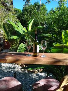 a bottle of wine and two glasses on a wooden table at Bosque Azul Picaflor in Minca
