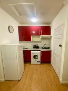 a kitchen with red cabinets and a white refrigerator at Penthouse studio with 2 double beds & smart TV. Great London Location in London