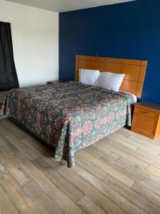 um quarto com uma cama e piso em madeira em Ranger Motel em El Reno