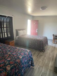 um quarto de hotel com duas camas e uma porta vermelha em Ranger Motel em El Reno