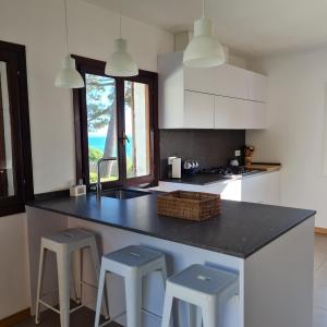a kitchen with a black counter top and two stools at Chalet sobre playa canelas, EN SANXENXO in Sanxenxo