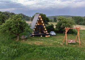 a small cabin with a playground and a car parked in a field at Blackcherry_Ukraine in Chereshenka