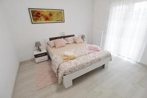 a white bedroom with a bed with pink pillows at Apartments with a parking space Umag - 21460 in Umag