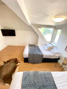 a attic bedroom with two beds and a window at Penthouse studio with 2 double beds & smart TV. Great London Location in London
