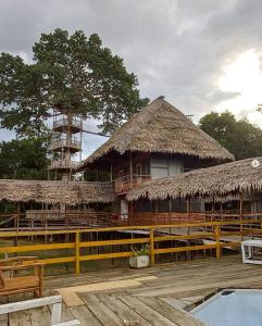un bâtiment avec un toit de paille et un bâtiment avec des chaises dans l'établissement Ceiba Amazon Lodge, à Iquitos
