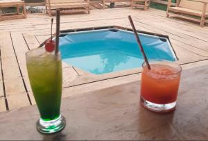 two drinks sitting on a table next to a swimming pool at Ceiba Amazon Lodge in Iquitos