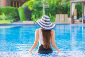 a woman in a hat sitting in a swimming pool at Executive Santa Monica Suites in Los Angeles