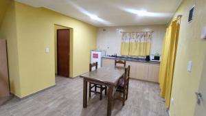 a kitchen with yellow walls and a wooden table at Cabañas Berenice in Malargüe