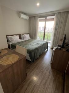 a bedroom with a bed and a desk and a window at Via Premiere Suite 710B in Rio de Janeiro