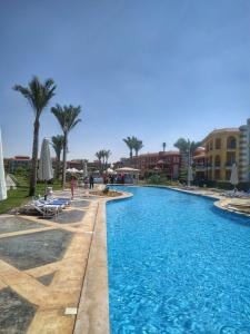 a swimming pool at a resort with palm trees and buildings at Porto Matrouh for FAMILIES ONLY in Marsa Matruh