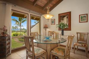 a dining room with a glass table and chairs at Aston At Poipu Kai in Koloa