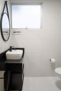 een witte badkamer met een wastafel en een spiegel bij Cidade das Bicicletas in Joinville