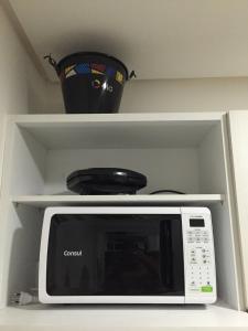 a white microwave oven sitting on a shelf at Manawa Beach Flat A24 - Centro Porto de Galinhas in Porto De Galinhas