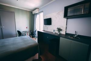 a bedroom with a bed and a sink and a table at Flat BOUTIQUE em frente ao metrô MOEMA in Sao Paulo