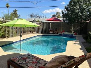 a swimming pool with an umbrella and chairs at Encanto Cactus Flower Casita in Phoenix