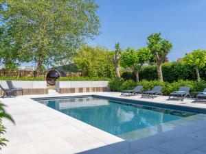 Luxury holiday home in Kortrijk with wellness and heated pool في كورتريك: مسبح وكراسي صالة ومسبح