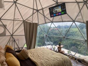 a bedroom with a large room with a tv in a tent at Poas Volcano Observatory Lodge & Glamping in Poasito