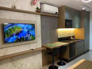 a kitchen with a television on a wall with a counter at Studio I Patteo Bosque Maia in Guarulhos