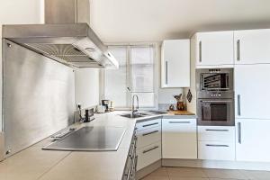 une cuisine avec des armoires blanches et des appareils en acier inoxydable dans l'établissement Fleurs de Nice furnished flat, à Nice