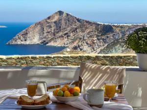 uma mesa com uma taça de fruta e dois copos de sumo em Aegean Balcony Studio em Áno Meriá