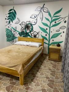 にあるEcohotel La Reservaのベッドルーム1室(花の壁画が壁に施されたベッド1台付)